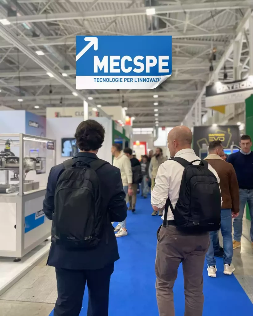 Visitatori e professionisti percorrono i corridoi del MECSPE tra stand di automazione e tecnologie per l'innovazione industriale.